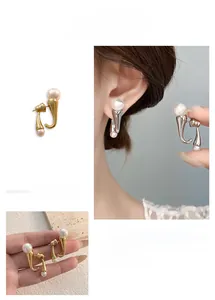 Detail showing gold and silver pearl J-hook earrings being worn and held for scale