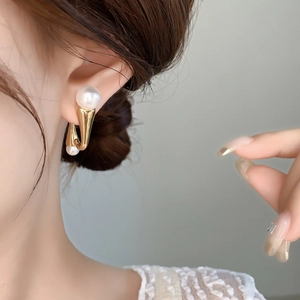Minimalist gold U-shaped pearl earrings with large and small pearls worn by a model