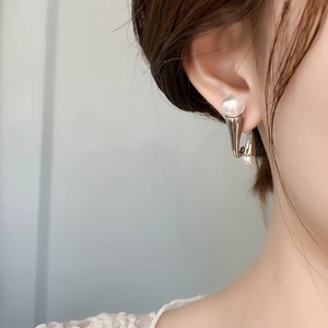 Close-up of geometric S925 silver earrings with layered pearls worn on the ear
