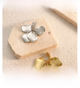 Macro shot of gold and silver flower-shaped earrings with zircon inlay on stone
