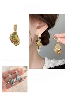 Macro detail of multi-layered shell shaped earrings with cubic zirconia and metallic finish