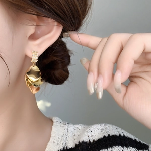 Detail of gold layered petal earrings with cubic zirconia stud on a female model