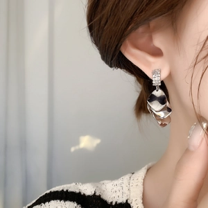 Close-up of silver layered shell-shaped earrings with zircons on female model