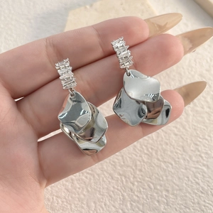 Detail of silver layered shell-shaped metal earrings with sparkling zircon stones
