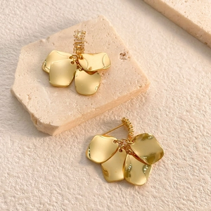 Close-up of golden petal drop earrings with micro-set cubic zirconia on textured stones