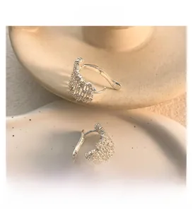 Detail of silver wavy hoop earrings with pave diamonds on a ceramic plate