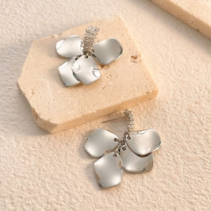 Detailed macro view of silver flower petal earrings with zircon accents on stone surface