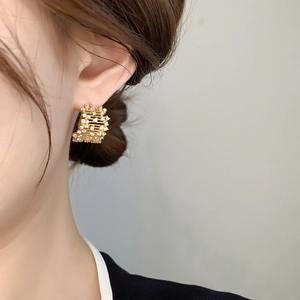Close-up of elegant gold layered hoop earrings with zircon pavé on a model's ear