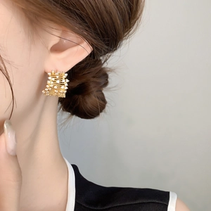 Detail of vintage French gold earrings with full crystal pavé and wavy metal texture