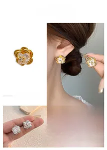Detailed view of 18K gold and silver rose earrings with sparkling zircon flower center
