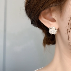 Detail of 18K gold plated camellia flower earrings with sparkling zircon center on model