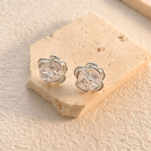 Macro detail of silver flower earrings featuring sparkling zircon and hollowed petals