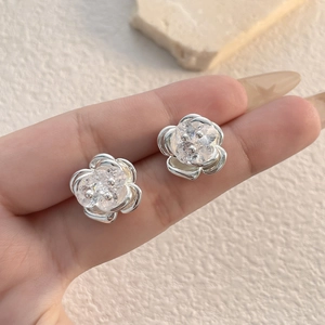 Elegant silver flower stud earrings with sparkling cubic zirconia on a minimalist background