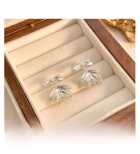 Close-up of silver bow earrings with lace fan charms inside a wooden jewelry box
