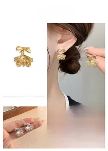 Macro detail of bow-knot lace fan earrings in gold and silver finish for women