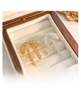 Detail of silver and gold lace bow earrings with sparkling white zircons in a jewelry box