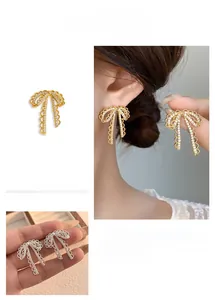 Detailed view of silver bow earrings with lace texture and shimmering zircon fringe