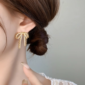 Detail shot of gold-plated lace bow earrings with sparkling micro-set crystals