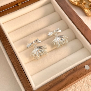 Detail view of silver bow earrings with lace scalloped drops in a wooden jewelry box