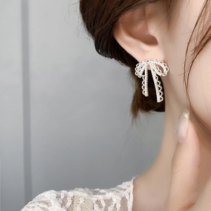 Close-up of S925 silver lace bow earrings with white zircons worn on model ear