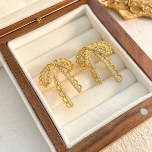 Macro shot of gold bow tassel earrings with sparkling cubic zirconia in a jewelry box