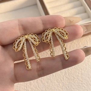 Detail of S925 silver needle bow earrings with gold plating and white zircon inlay
