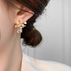 Detailed close-up of elegant gold stud earrings with shimmering pearls and zircon stones