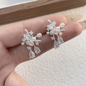Close-up of elegant silver earrings with clustered white pearls and sparkling zircons