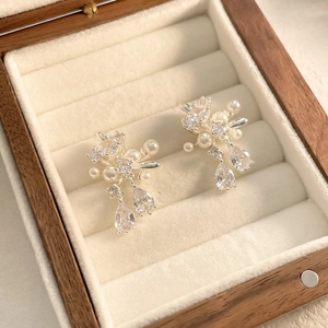 Close-up of elegant silver earrings with pearls and marquise-cut zircons in a wooden box