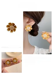 Detailed view of matte gold flower earrings with sparkling crystal center studs