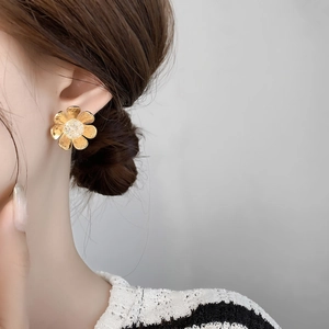 Close-up of elegant gold flower stud earrings with matte texture and zircon inlay