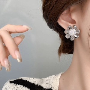 Close-up of silver flower earrings with hammered petals and sparkling zircon stones