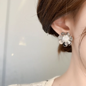 Elegant silver flower stud earrings with sparkling zircon center worn by a model