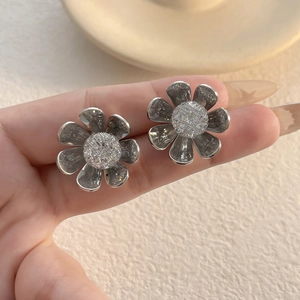Macro detail of silver sunflower earrings with sparkling center crystals and 3D petals