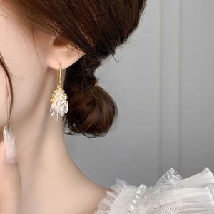 Detailed view of elegant gold firework fringe earrings with crystal beads on a model