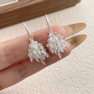 Elegant fireworks design earrings with zircon crystals held by hand on white texture