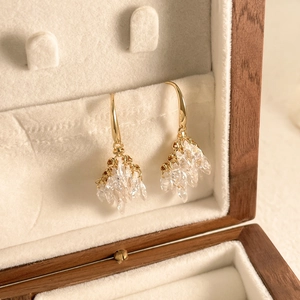 Macro shot of firework zircon tassel earrings with crystal clusters on white velvet