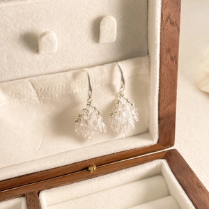 Close-up of ice crystal fireworks dangle earrings on velvet lining of a wooden box