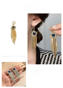 Détail de longues boucles d'oreilles à pompons en zircon et pierres bleues dorées