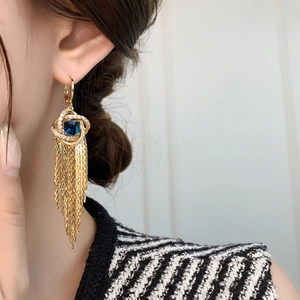 Gros plan de boucles d'oreilles pendantes dorées avec pierre bleue sur un mannequin