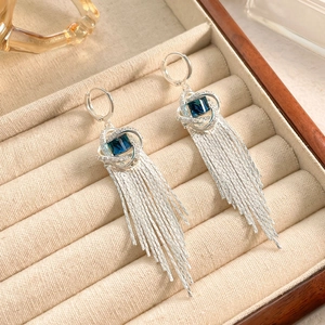 Gros plan sur des boucles d'oreilles à franges argentées avec zircon bleu foncé