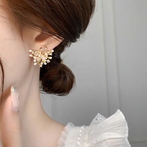 Close-up of golden butterfly earring with delicate white pearls and sparkling cubic zirconia