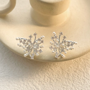 Macro view of silver butterfly stud earrings with white pearls and sparkling rhinestones