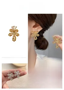 Detailed view of gold plated twisted bow earrings featuring three teardrop zircon stones