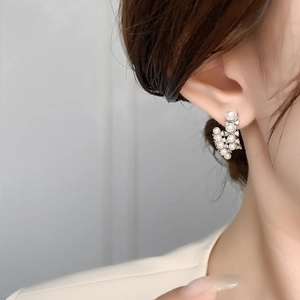 Primo piano di orecchini a grappolo di perle e zirconi indossati da una modella elegante