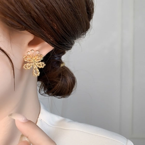 Detail of twisted gold bow earrings with cubic zirconia on a female model