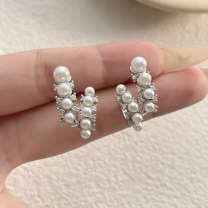 Dettaglio di orecchini vintage con perle e zirconi tenuti in mano per mostrare la scala