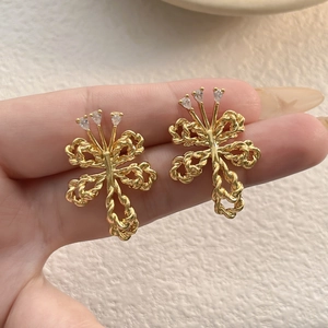 Detailed view of gold-plated twisted bow earrings with sparkling zircon gemstones