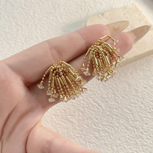 Detail shot of shimmering zircon firework fringe earrings with gold-tone beaded chains