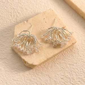 Detailed close-up of fan-shaped silver earrings with sparkling zircon fringe on stone
